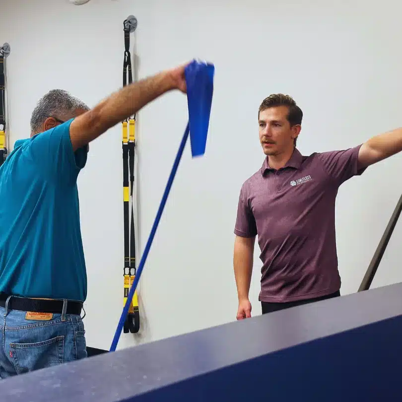 Dr. Seth Little supervising patient performing shoulder rehab with resistance band in Alliance Town Center.